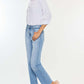 Woman wearing high waist raw hem straight jeans with a white blouse and sandals, showcasing a chic casual look.