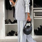 Stylish woman in gray denim lapel collar top and pants set, accessorized with a chic black handbag.