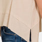 Side view of a beige exposed seam slit round neck tank paired with blue jeans.