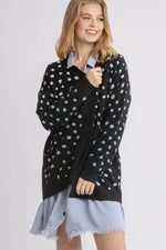 Stylish woman in a black polka dot open front cardigan over a denim dress, showcasing a relaxed look and playful vibe.