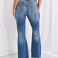 Woman wearing Risen Hazel High Rise Distressed Flare Jeans with frayed hems, showing back pocket details.