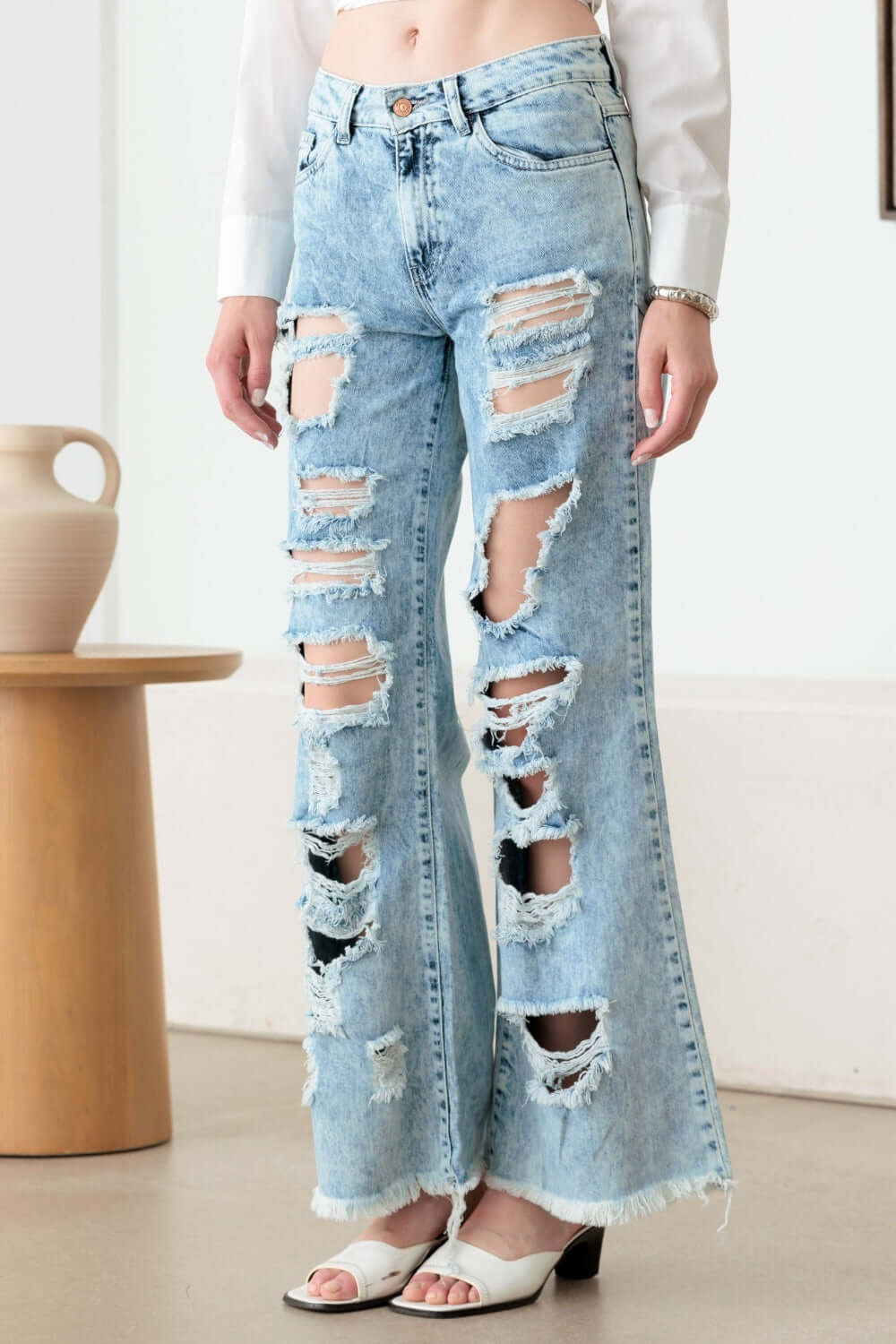 Distressed frayed hem flare jeans with ripped detailing for a trendy, edgy look, featuring classic 5 pockets, zip fly, and button closure.