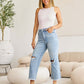 Woman wearing Tummy Control High Waist Raw Hem Distressed Jeans with a white top, showcasing RFM Jeans in a stylish living room setup