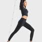 Woman in black Millennia sports leggings stretching with resistance band, showcasing activewear versatility and style.