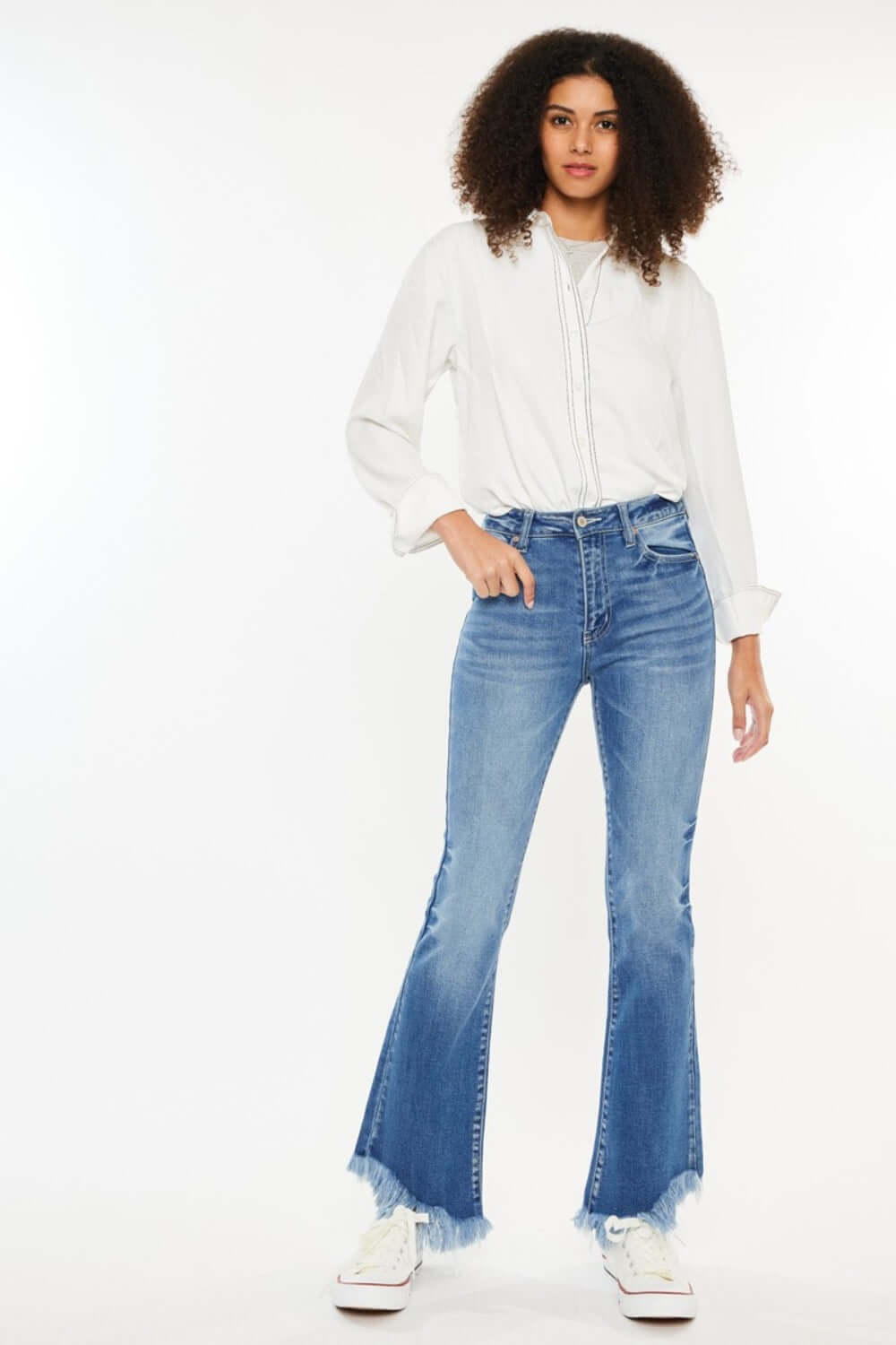 Woman modeling Kancan High Rise Frayed Hem Jeans with a relaxed fit and trendy raw hem, paired with a white shirt and sneakers.