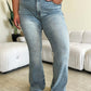 Woman wearing Judy Blue high waist flare jeans in light wash while standing in a stylishly furnished room.