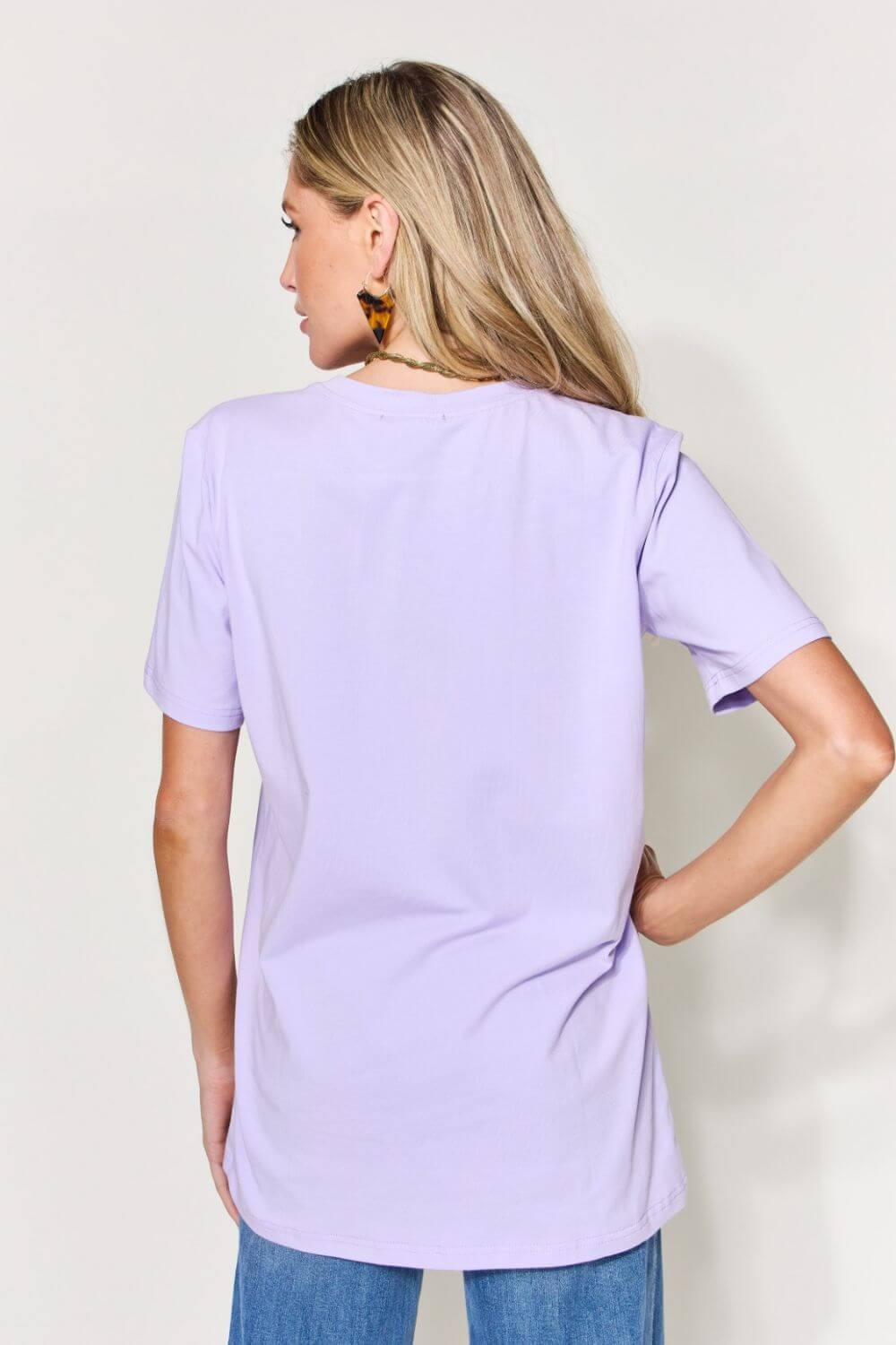 Woman wearing a lavender graphic round neck short sleeve t-shirt with jeans, back view