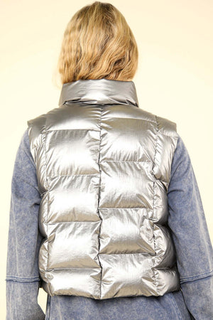 Shiny metallic zip up puffer vest with high neck and side pockets, showcasing a bold, modern look for winter layering.