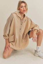 Stylish model wearing beige Aemi+Co Slit Half Snap Oversize Hoodie, featuring a unique split design and cozy pockets.