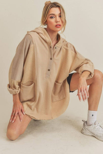 Stylish model wearing beige Aemi+Co Slit Half Snap Oversize Hoodie, featuring a unique split design and cozy pockets.