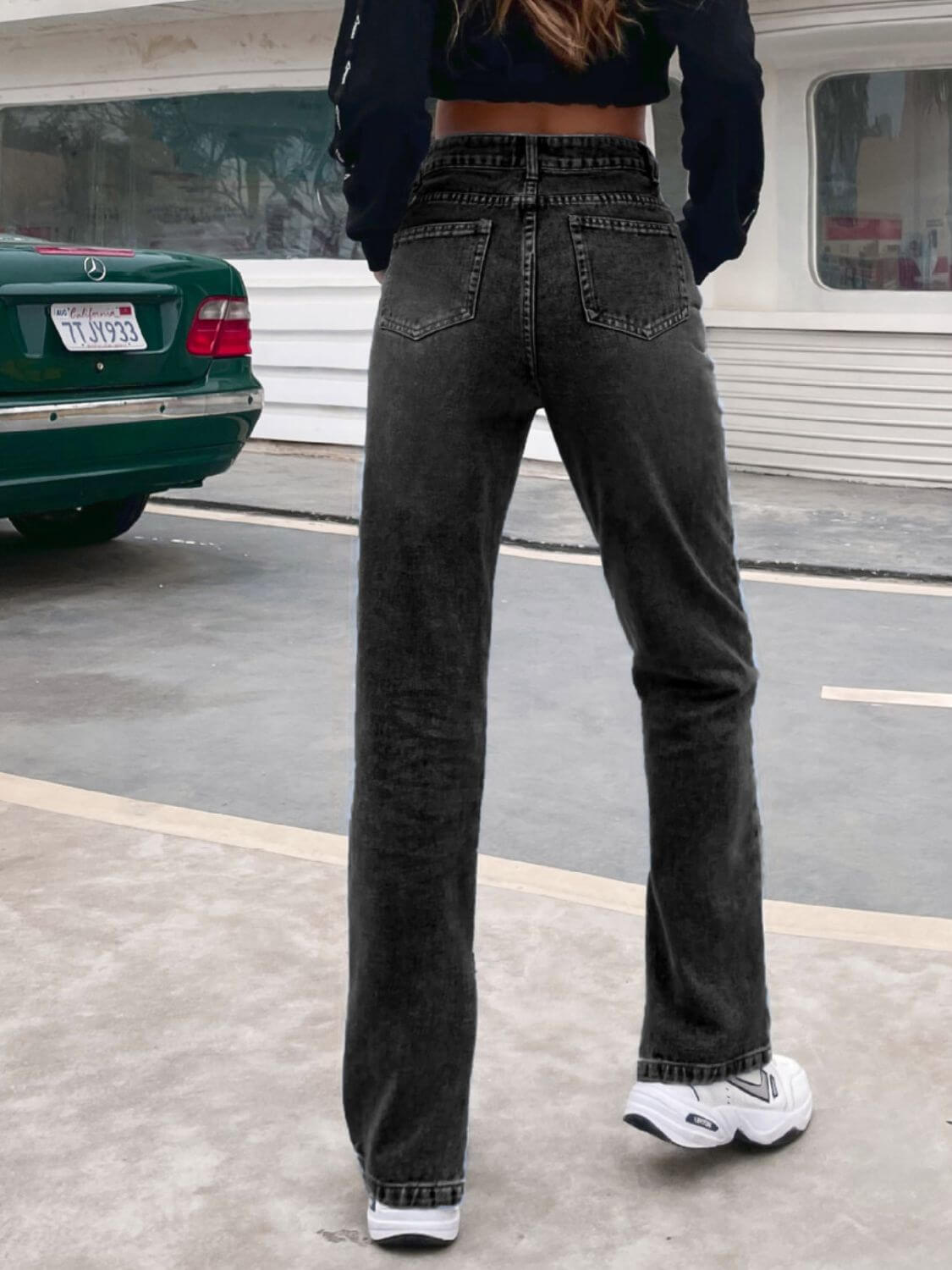 Woman wearing Bella Road Side Slit High Waist Jeans with Pockets, standing outdoors facing away, showing back details.