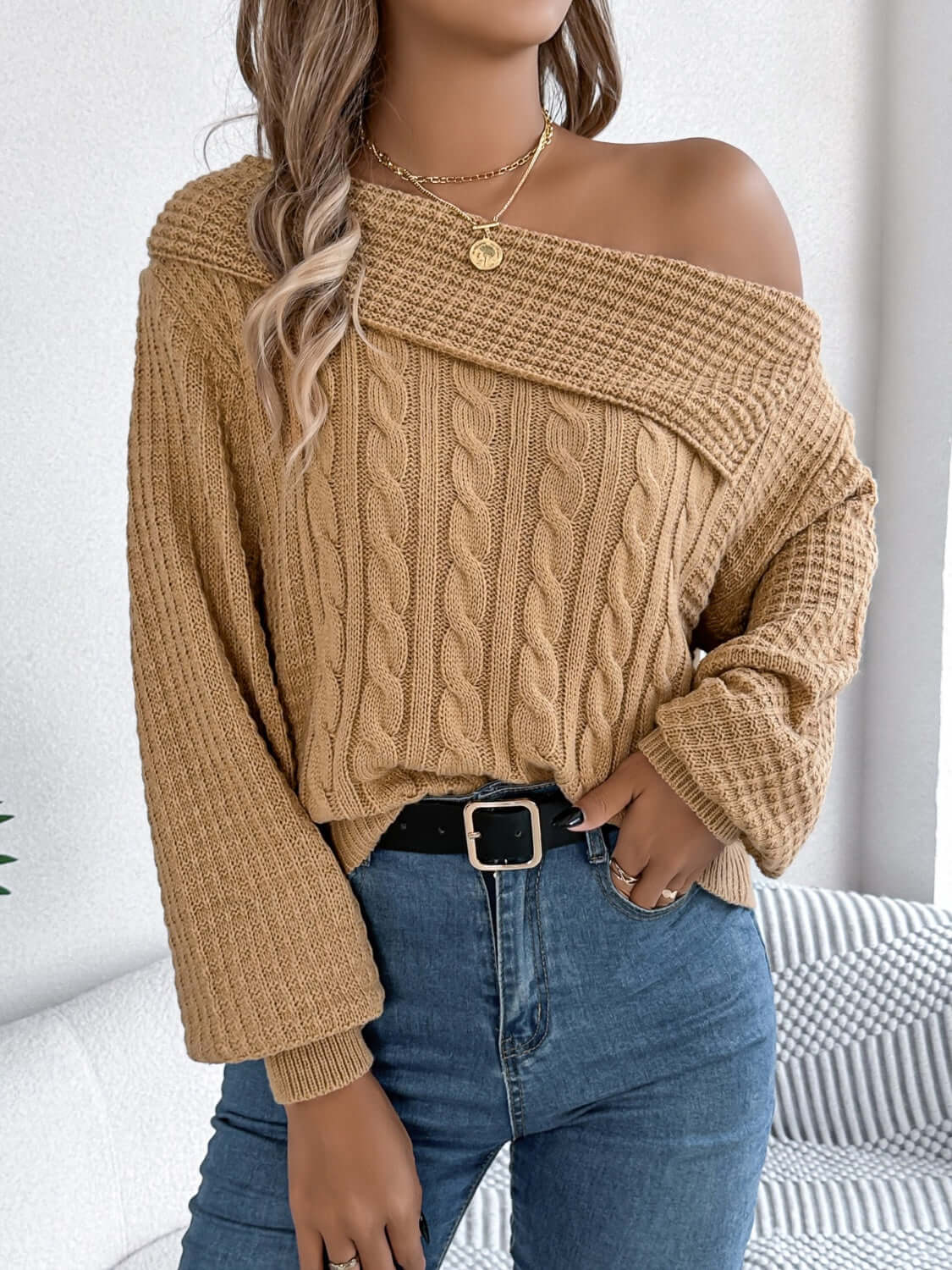 Woman wearing Bella Road Cable-Knit One Shoulder Long Sleeve Sweater in beige, paired with jeans for a cozy and stylish look.