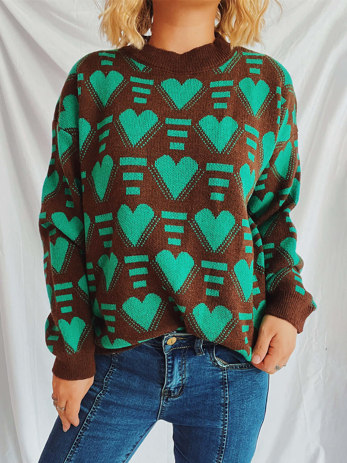 Woman wearing Bella Road Heart Contrast Long Sleeve Dropped Shoulder Sweater in brown and green hearts design.