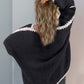 Woman wearing Double Take Contrast Cardigan in black, showing open front and dropped shoulder design from the back.