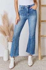 Woman wearing Risen Jeans High Rise Ankle Flare Jeans with white ankle boots, showcasing denim's flattering fit and stylish design