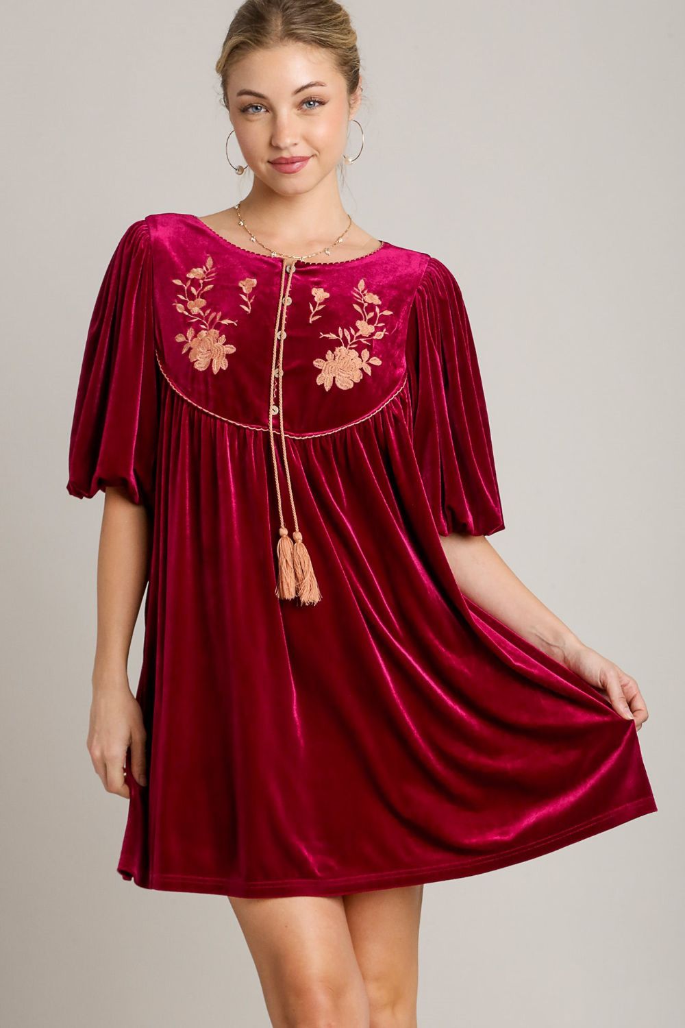 Elegant woman wearing a red velvet mini dress with embroidered flowers and tassels, perfect for special events.