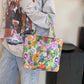 Person holding a colorful painted canvas handbag with floral design and a zipper, wearing casual clothes in a room with black furniture.