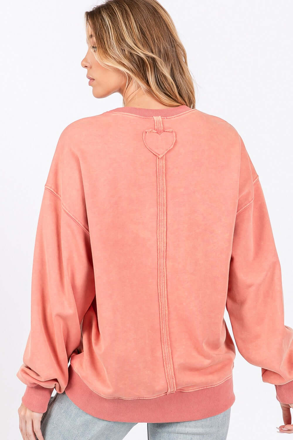 Back view of woman wearing LOVE Path Applique Drop Shoulder Sweatshirt with heart patch and round neckline.