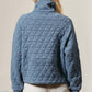 Woman wearing blue quilted half zip long sleeve sweatshirt with a pocket and white shorts, showcasing cozy chic style.