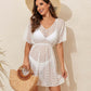 Woman wearing V-Neck Half Sleeve Cover-Up in sheer, stretchy polyester with a straw hat and handbag, standing against a neutral backdrop.