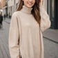 Woman wearing a beige turtleneck sweater with side slits and dropped shoulders, perfect for cozy and stylish fall fashion.