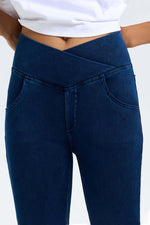 Dark blue bootcut jeans with a crossover high waist design and front pockets, showcasing stylish comfort and flexibility.