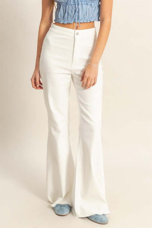 Model wearing HYFVE high-waist washed flared jeans with raw hem detail, paired with a blue crop top and stylish blue shoes.