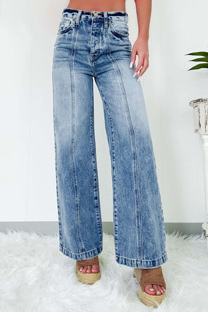 Woman wearing high waist wide leg jeans with pockets, slightly stretchy denim fabric, retro style, standing on a white fluffy rug.