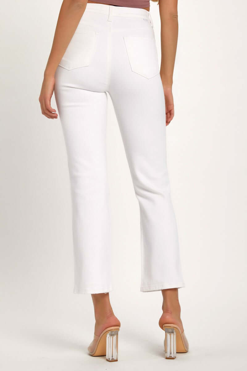 Woman wearing white cropped straight jeans, showcasing back pockets and clear heel sandals.