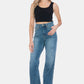 Woman wearing Judy Blue Full Size Tummy Control Raw Hem Straight Jeans with a black tank top and white sneakers.