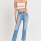 Woman wearing RISEN low rise crop slim straight jeans with raw hem, showcasing a stylish and versatile fashion look.