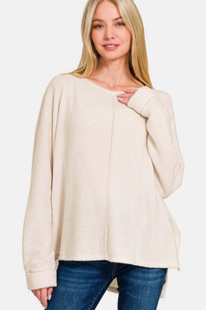 Woman wearing cream Zenana High-Low Side Slit Round Neck T-Shirt, showcasing its modern high-low hem and chic round neck design.