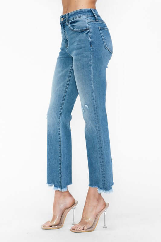 Side view of bytos Raw Hem Distressed Mid Rise Crop Jeans showcasing a cropped length and raw hem detail. Perfect for edgy style!