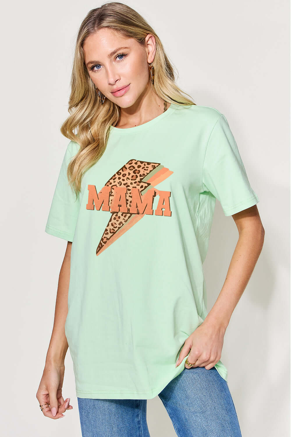 Woman wearing MAMA round neck short sleeve t-shirt in light green with leopard print design and blue jeans