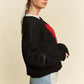 Model showcasing the Davi & Dani Contrast Heart Dropped Shoulder Sweater with a stylish black design and playful red heart.