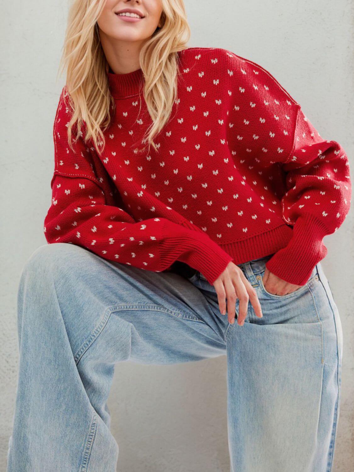 Woman wearing red patterned sweater with long sleeves and loose fit, paired with light blue jeans, showcasing cozy fall fashion.