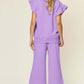 Woman wearing a lavender ruffle short sleeve top with drawstring wide leg pants set, viewed from the back.