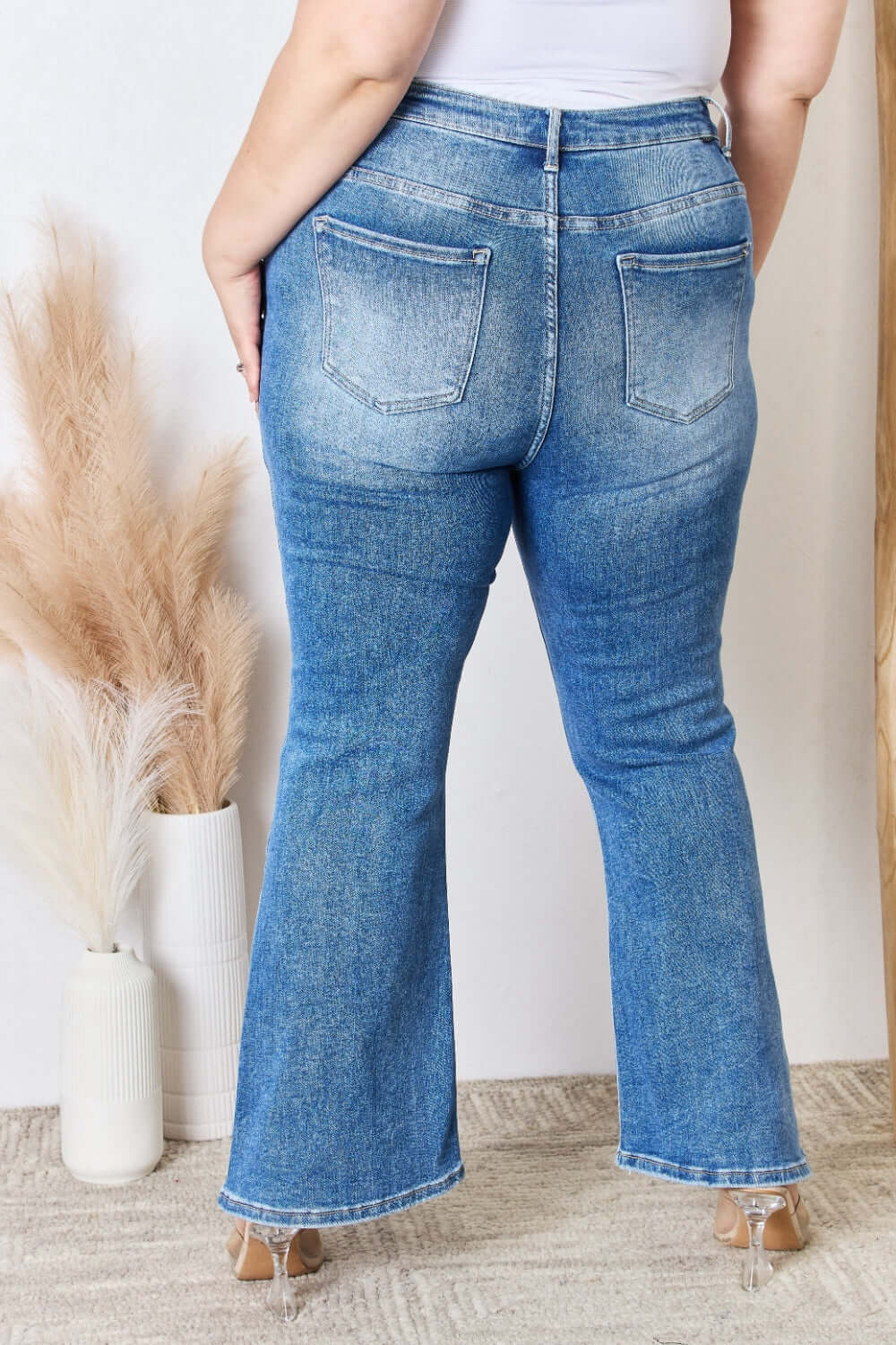 Back view of model wearing High Rise Ankle Flare Risen Jeans, showcasing flattering fit and quality stitching.