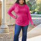 Woman wearing a pink round neck long sleeve t-shirt made of slightly stretchy rayon and spandex, paired with jeans, in an outdoor setting.