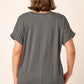 Back view of a woman wearing a grey V-neck rolled short sleeve T-shirt, showcasing the rolled sleeves and relaxed fit.