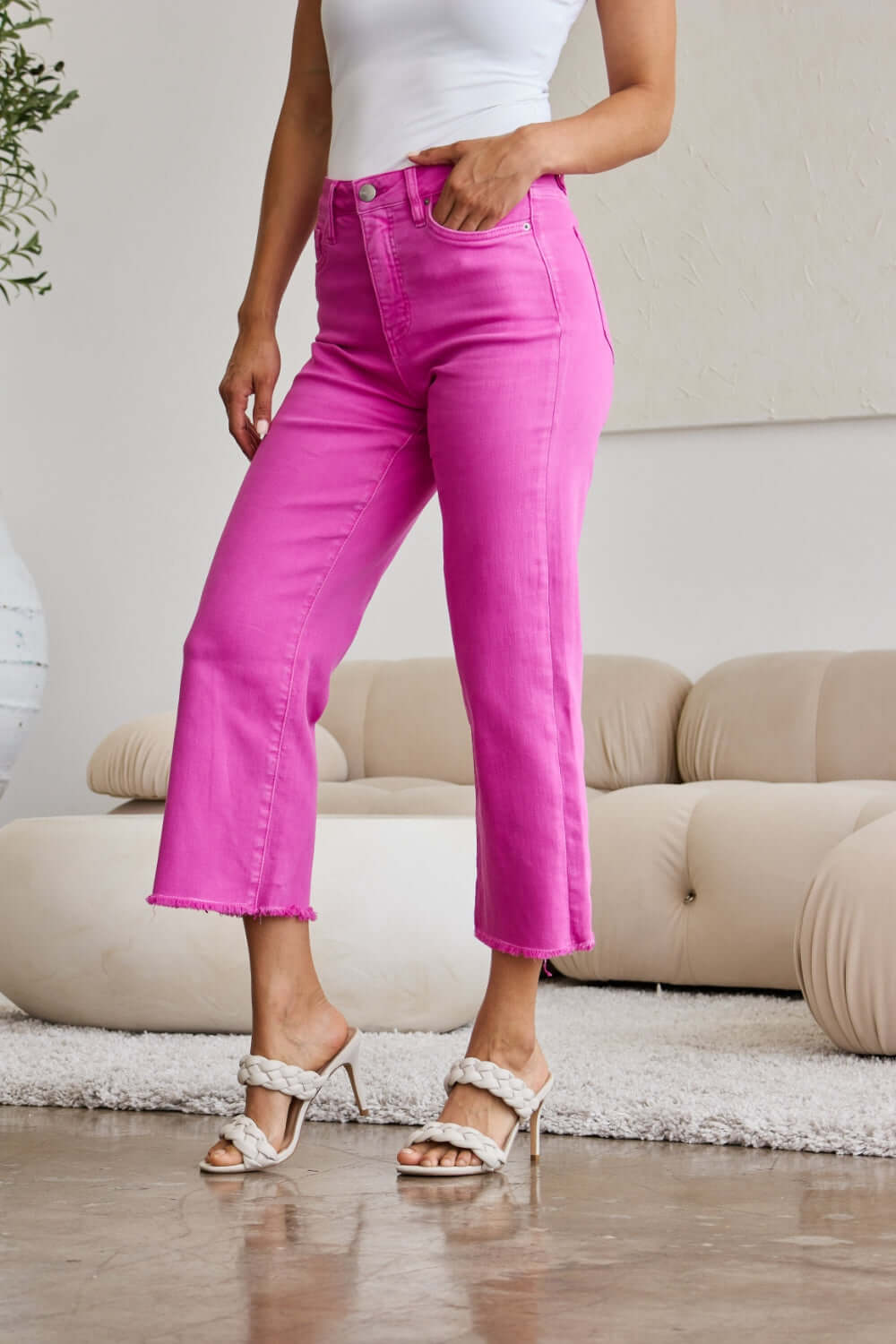 Woman modeling RFM Jeans Crop Chloe Full Size Tummy Control High Waist Raw Hem Jeans in vibrant pink.