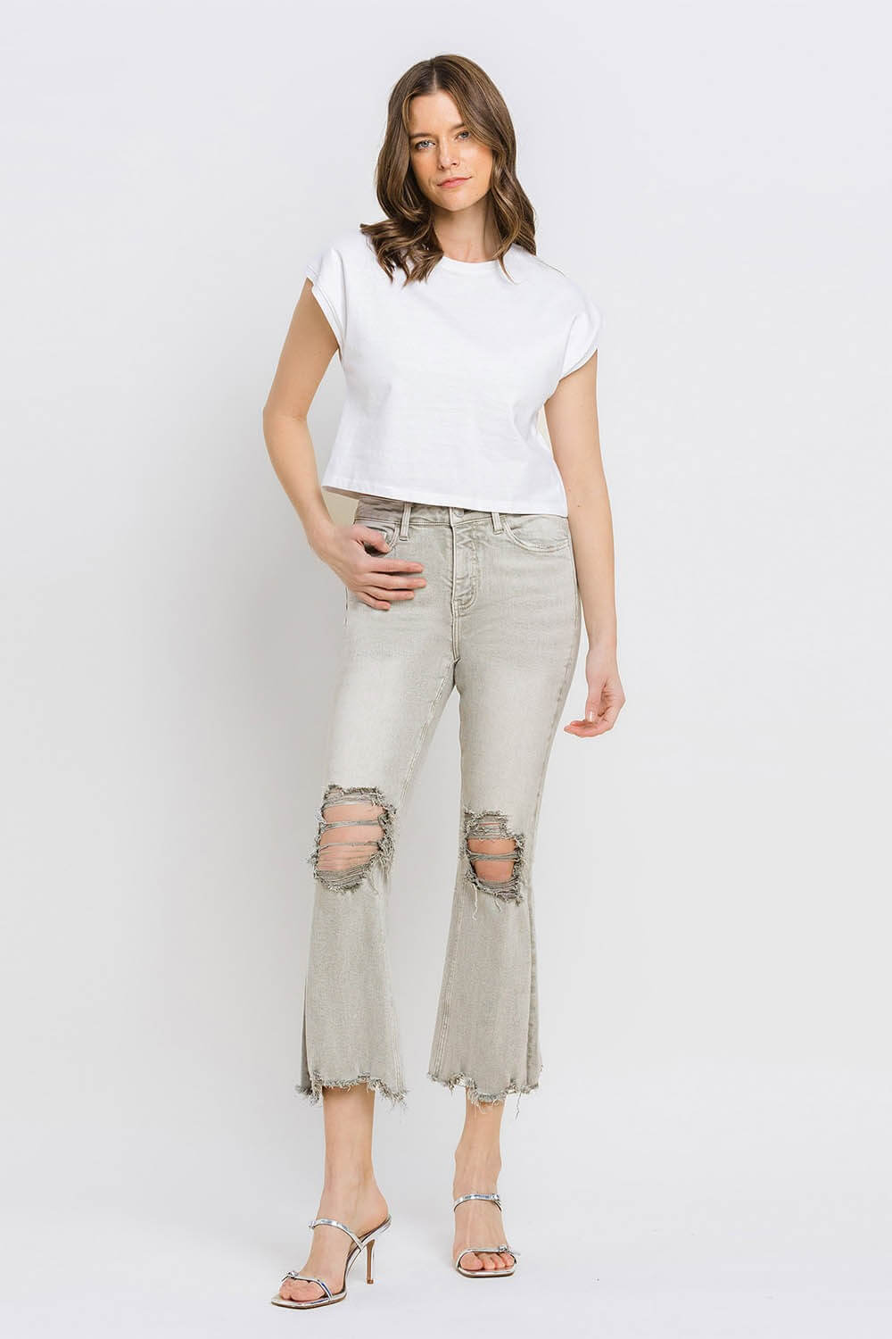 Woman wearing Lovervet distressed raw hem cropped flare jeans with a white t-shirt and high heels.