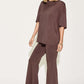 Woman wearing a bamboo drop shoulder T-shirt and flare pants set in brown with blue platform sandals.