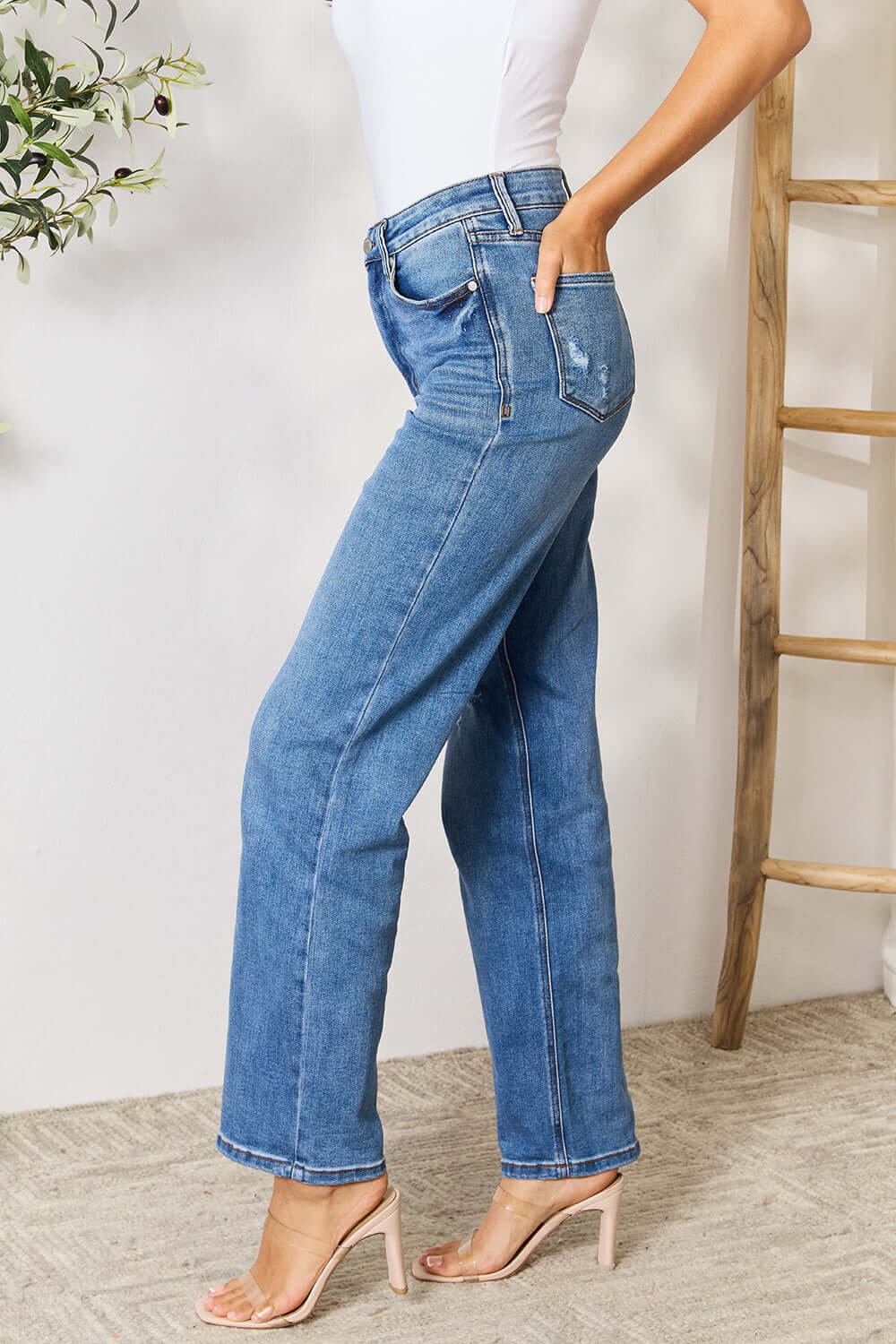 Woman wearing Judy Blue High Waist Distressed Jeans, full-size, side view showcasing classic fit and contemporary style with high waist design.