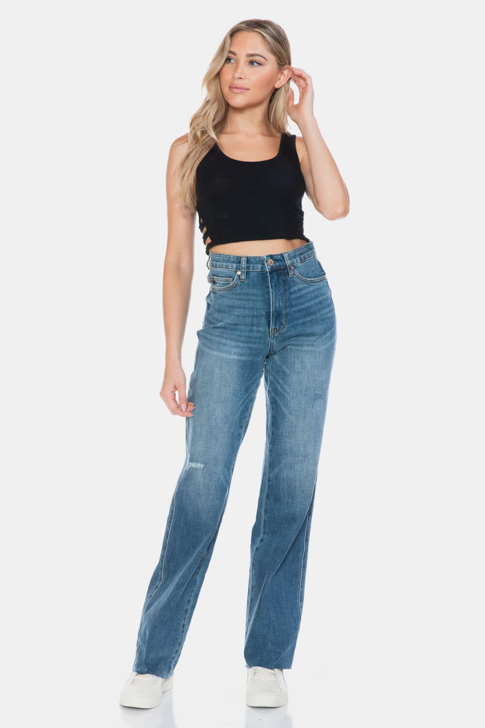 Woman wearing Judy Blue full size tummy control jeans with raw hem and high-waist design paired with black top.