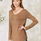 Woman wearing a luxurious brown long sleeve V-neck top made of rayon with a flattering neckline and versatile opaque design.