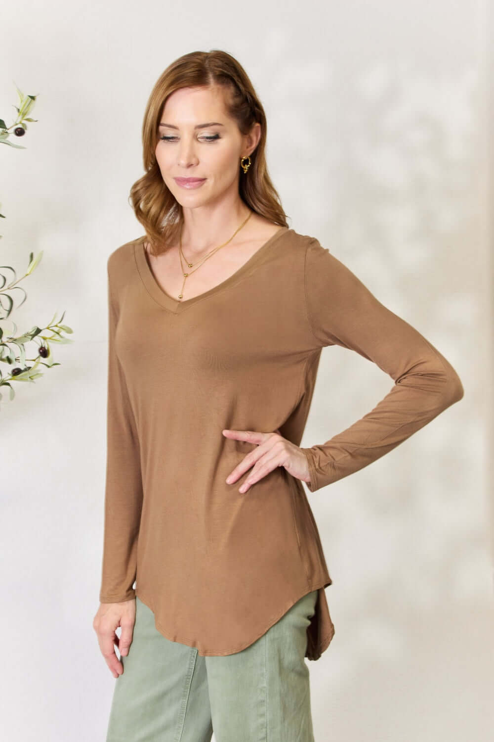 Woman wearing a luxurious brown long sleeve V-neck top made of rayon with a flattering neckline and versatile opaque design.