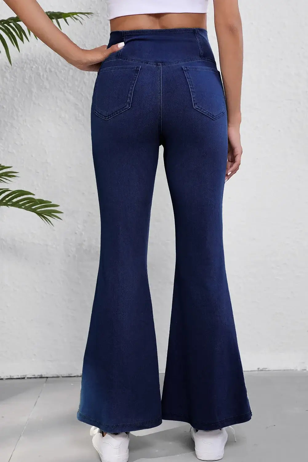 Back view of woman wearing Asymmetric Waist Flare Jeans, showcasing pocket details and flared legs for a stylish and comfortable fit