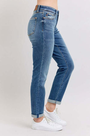 Judy Blue plus size mid rise skinny cuff jeans in blue with pockets, styled with white sneakers, side view.