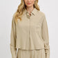 Woman wearing RISEN Button Down Long Sleeve Shirt in beige, featuring a classic design and front pocket.